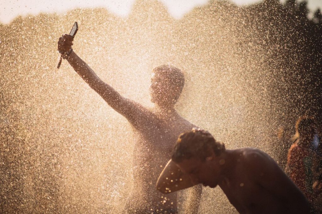 Men enjoying a refreshing water splash under the summer sun in Budapest.